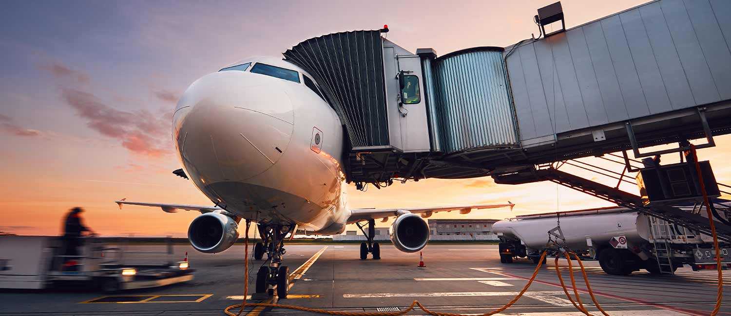 Airplane Connected to Jet Bridge with Ground Support Equipment in Background
